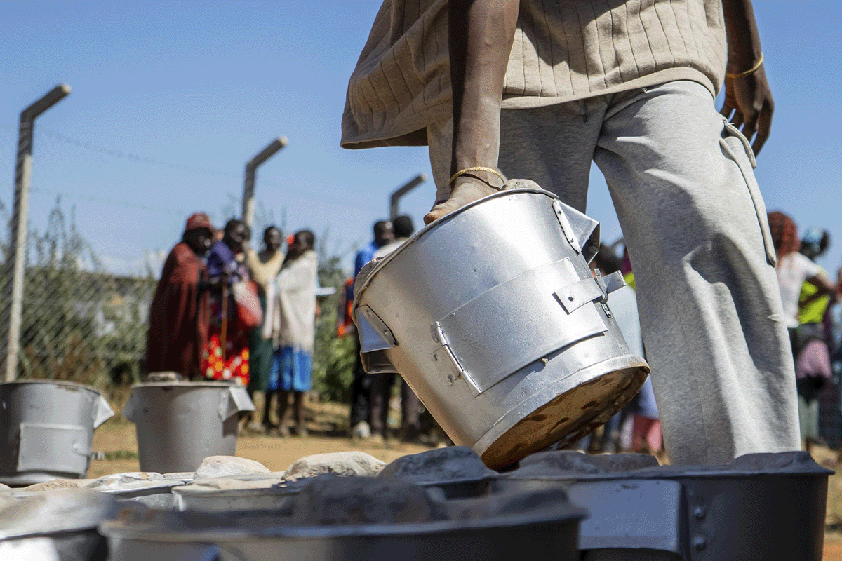 The cookstoves revolution in Cameroon_Close-up of DGB team member arranging cookstoves, local people in the background_visual 2