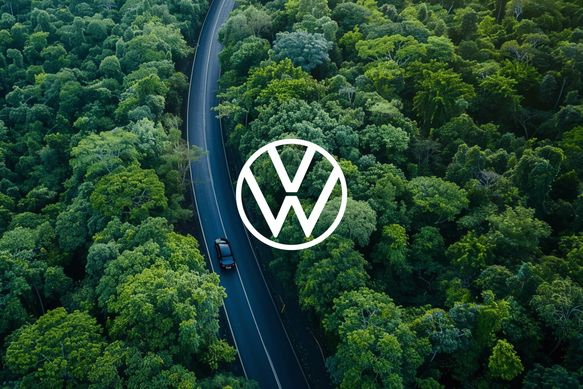 Volkswagens commitment to nature (-based solutions)_An aerial view of a car driving along a modern road through lush green hills and forests_visual 1